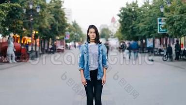 一个穿着时髦服装的漂亮女孩独自看着一个人站在步行街上的摄像机的时间流逝
